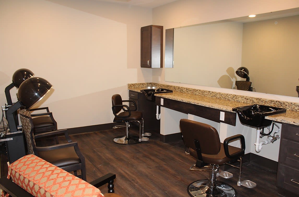 A modern hair salon interior with chairs, a large mirror, and a countertop.