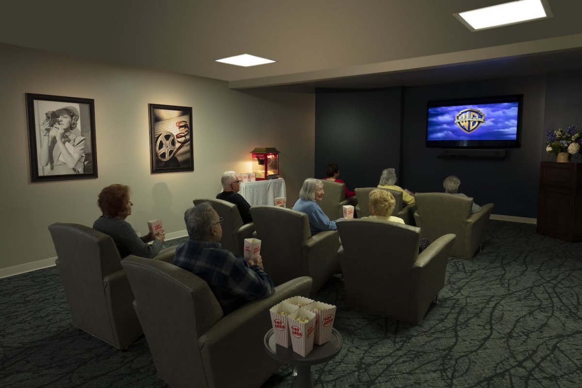 A group of elderly people enjoying a movie together in a cozy home theater setting.