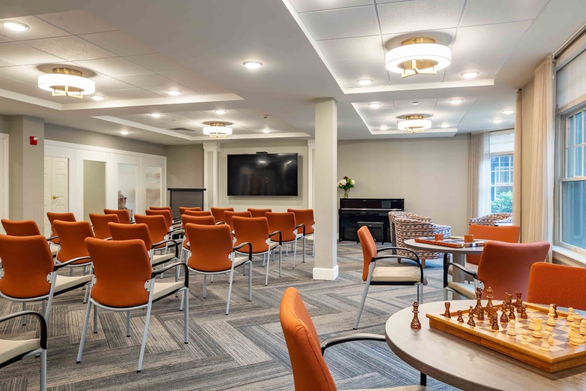 A modern conference room with orange chairs and a large screen for presentations.