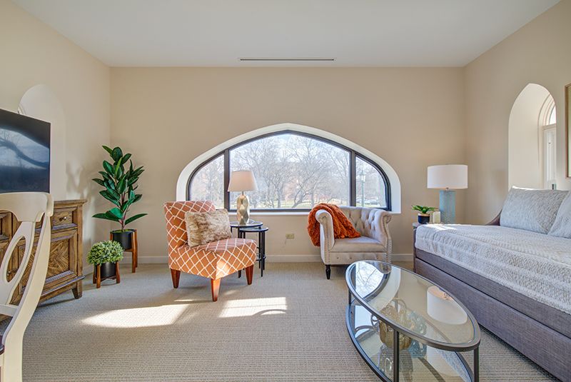 A modern living room with an arched window, featuring stylish furniture and vibrant decor.