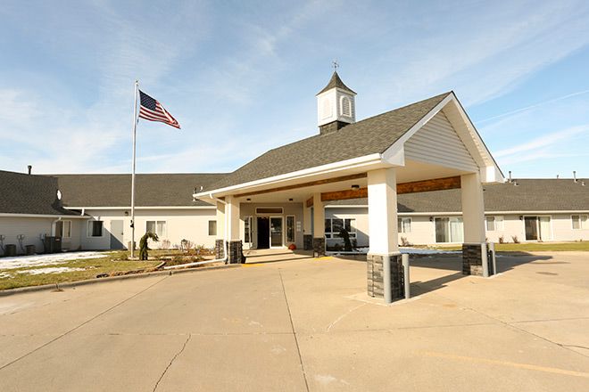 The image shows a building entrance with an American flag flying nearby.