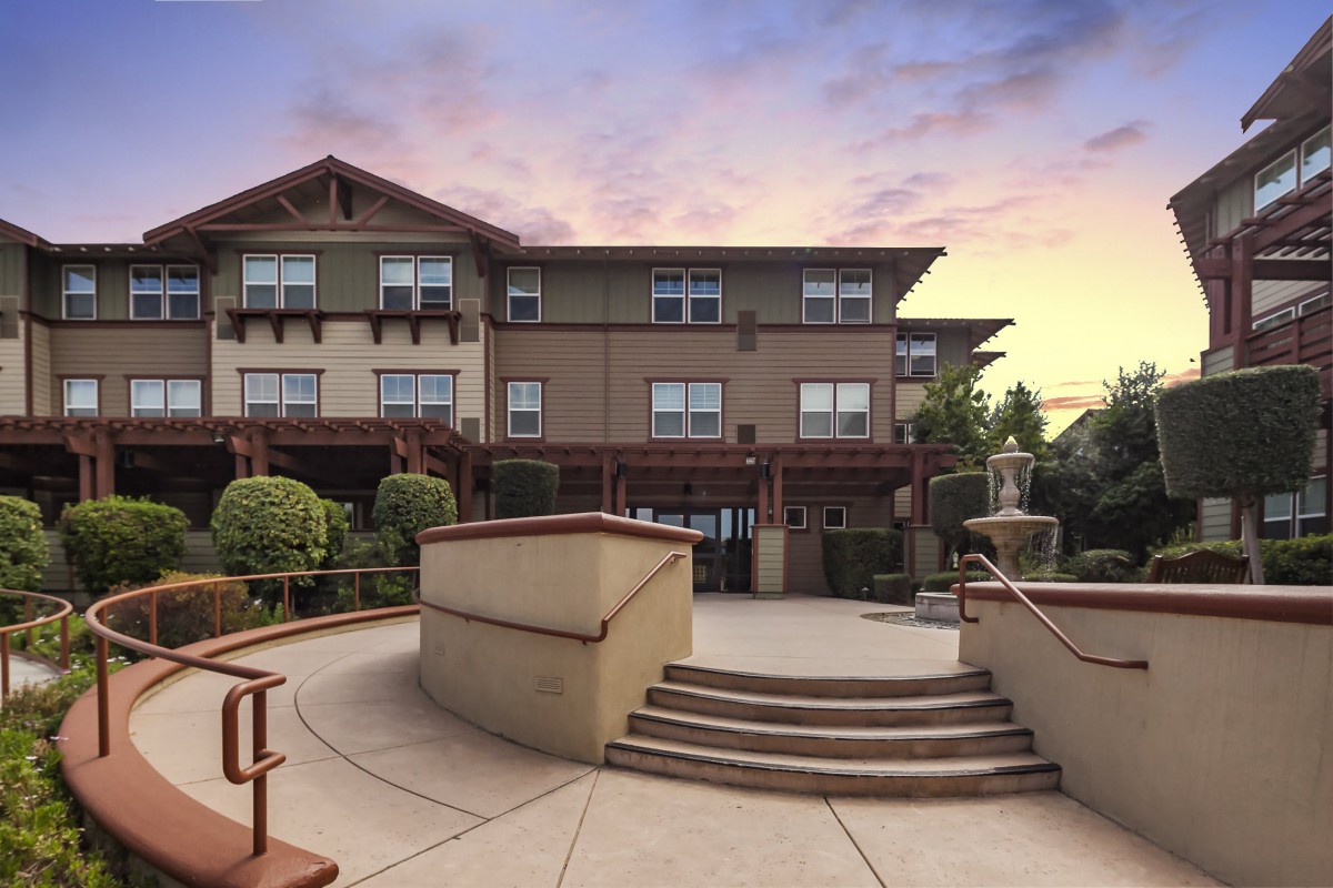 A residential building exterior with landscaped stairs at sunset.
