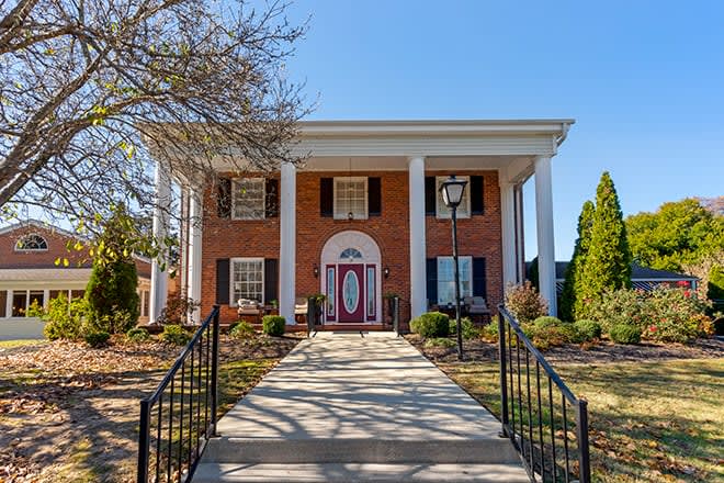 A classic colonial-style brick house with large columns and well-maintained landscaping.