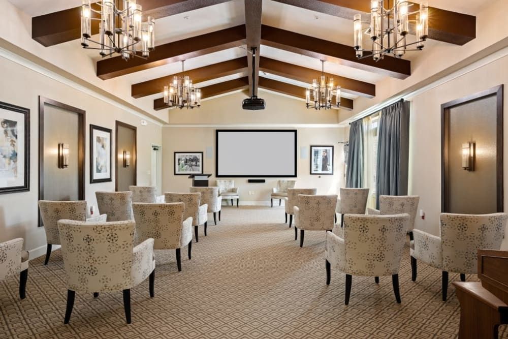 A well-appointed conference room with elegant seating, chandeliers, and a large projector screen.