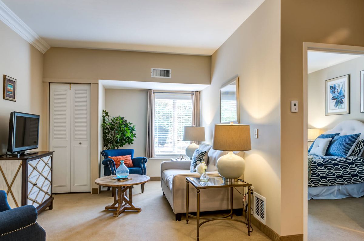 A cozy living room with a comfortable sofa, lamps, and a coffee table by the window.