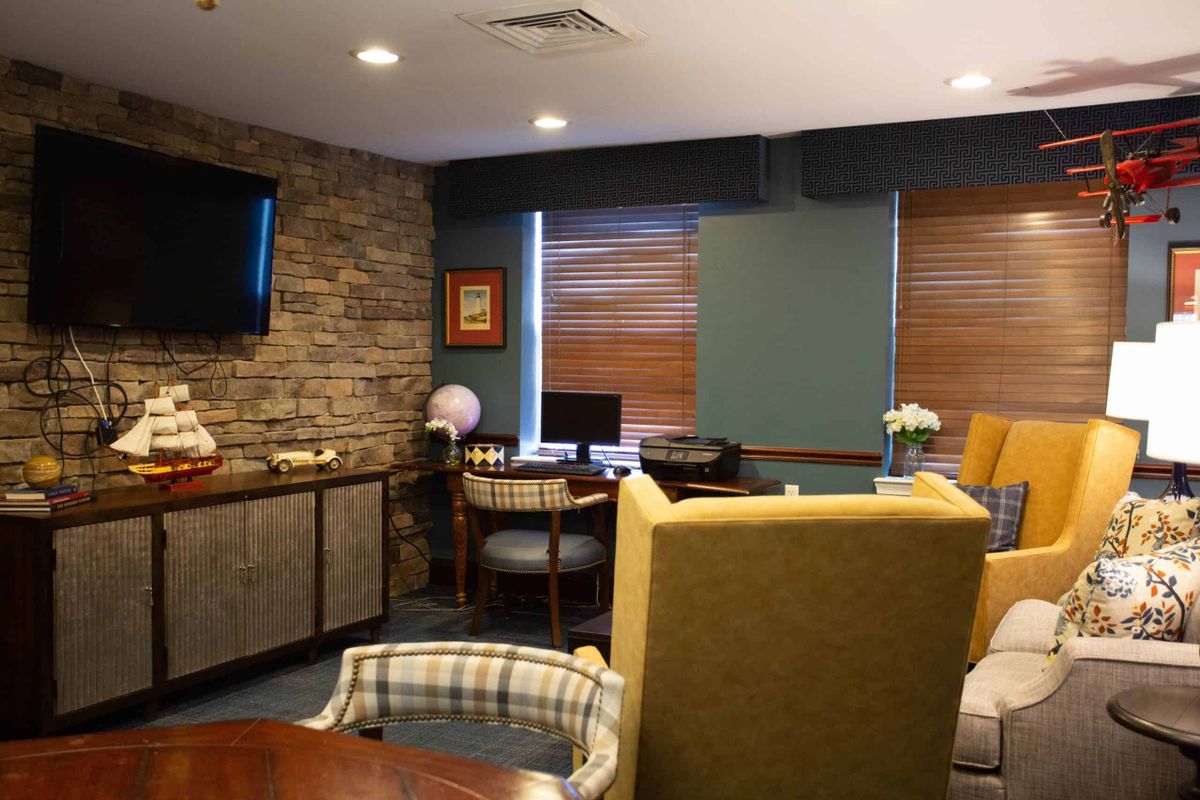 A cozy living room with a seating area, television, and desk by the window.