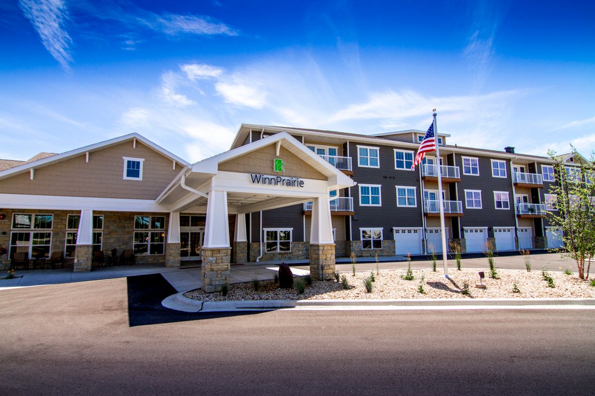 A modern hotel building with an entrance canopy, set under a clear blue sky.