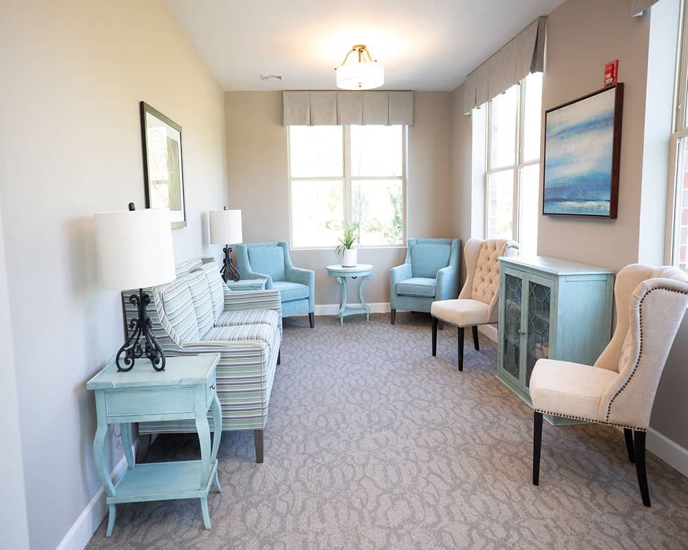 A bright living room with blue and beige furnishings and large windows.