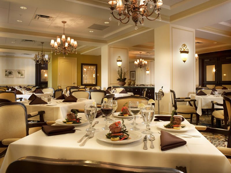 An elegant restaurant interior with beautifully set tables and chandeliers.