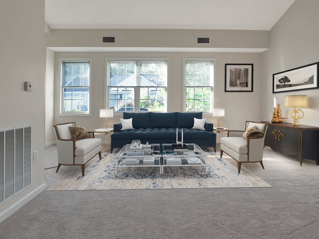 A modern living room with a navy blue sofa, two armchairs, and a glass coffee table, complemented by natural light from large windows.