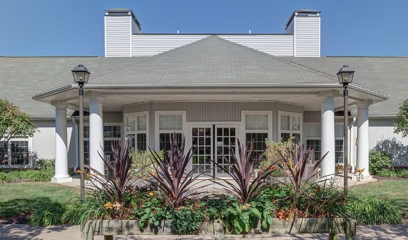 A house with a landscaped front yard featuring various plants and large windows.
