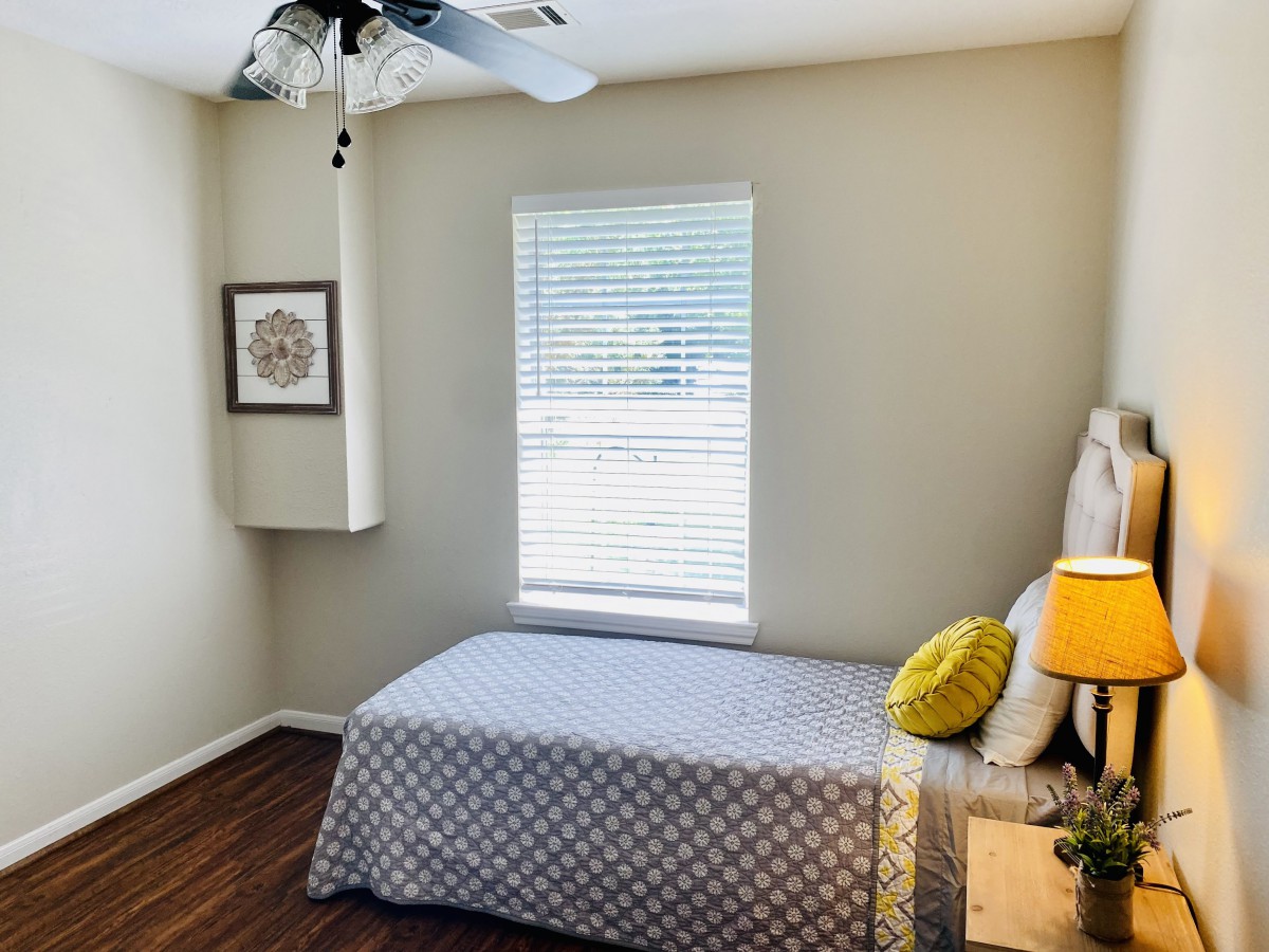 A minimalist bedroom with a single bed, lamp, and window.