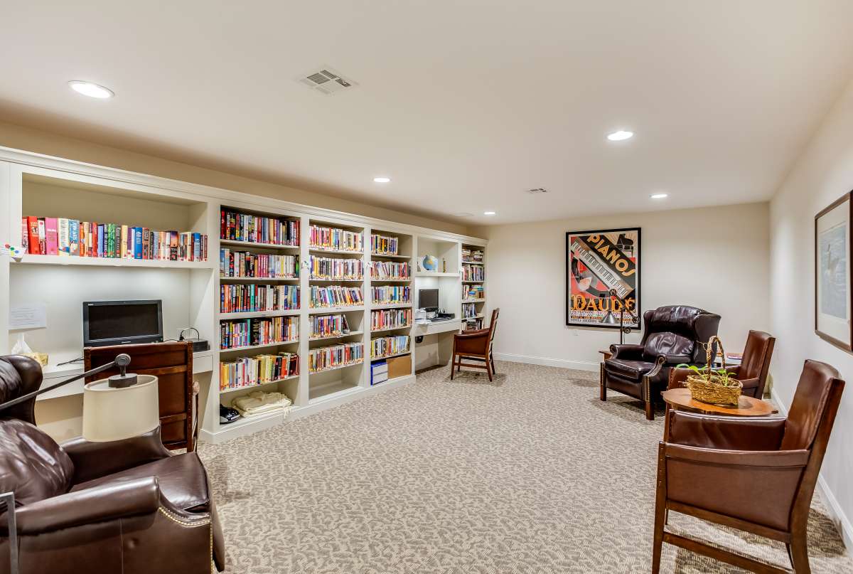 A cozy home library with bookshelves, comfortable seating, and colorful artwork.