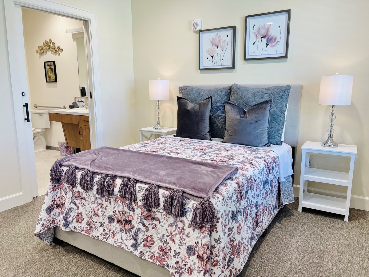 A cozy bedroom with a floral patterned bedspread, decorative pillows, and soft lighting from bedside lamps.
