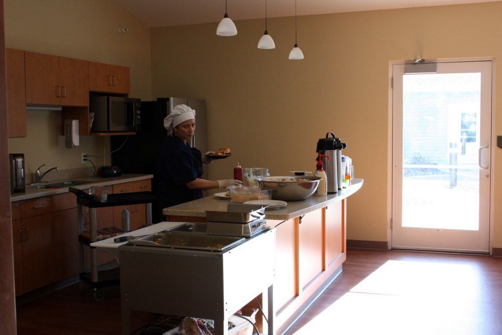 A chef working in a well-lit kitchen with various appliances and a countertop full of ingredients.