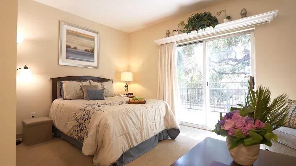 A cozy and well-lit bedroom with elegant decor and a large window.