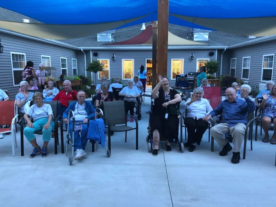 A group of seniors gathered outdoors in the evening, sitting in chairs and enjoying a community event.