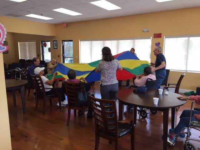 A group of people engaging in a parachute game inside a community center.