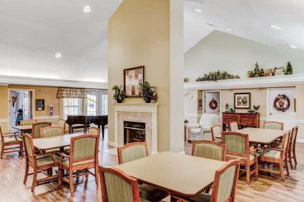 A well-decorated community dining area featuring tables, chairs, a fireplace, and a piano.