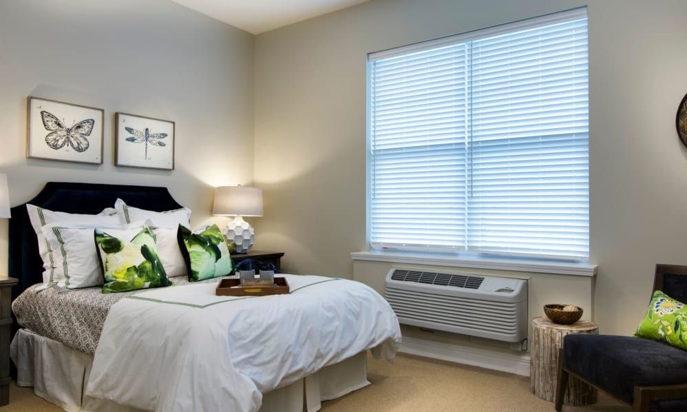 A cozy bedroom with a neatly made bed, decorative pillows, and a bedside lamp.