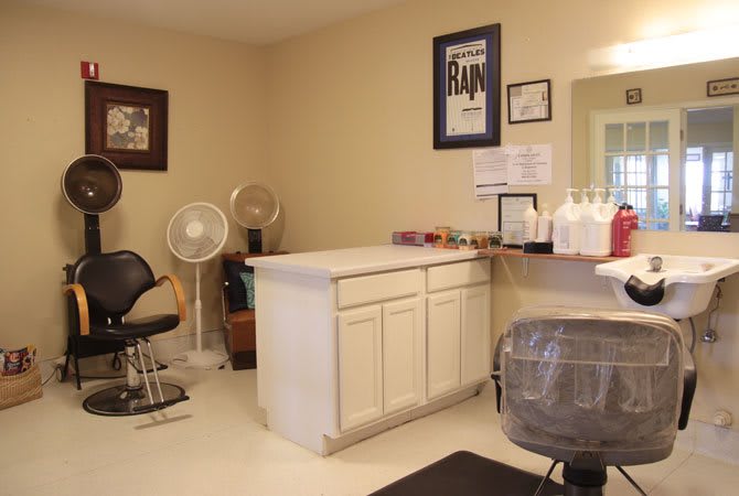 A cozy salon interior with styling chairs, a counter, and hair products neatly arranged.