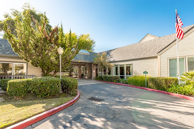 The entrance to a well-maintained building with surrounding trees and landscaping.