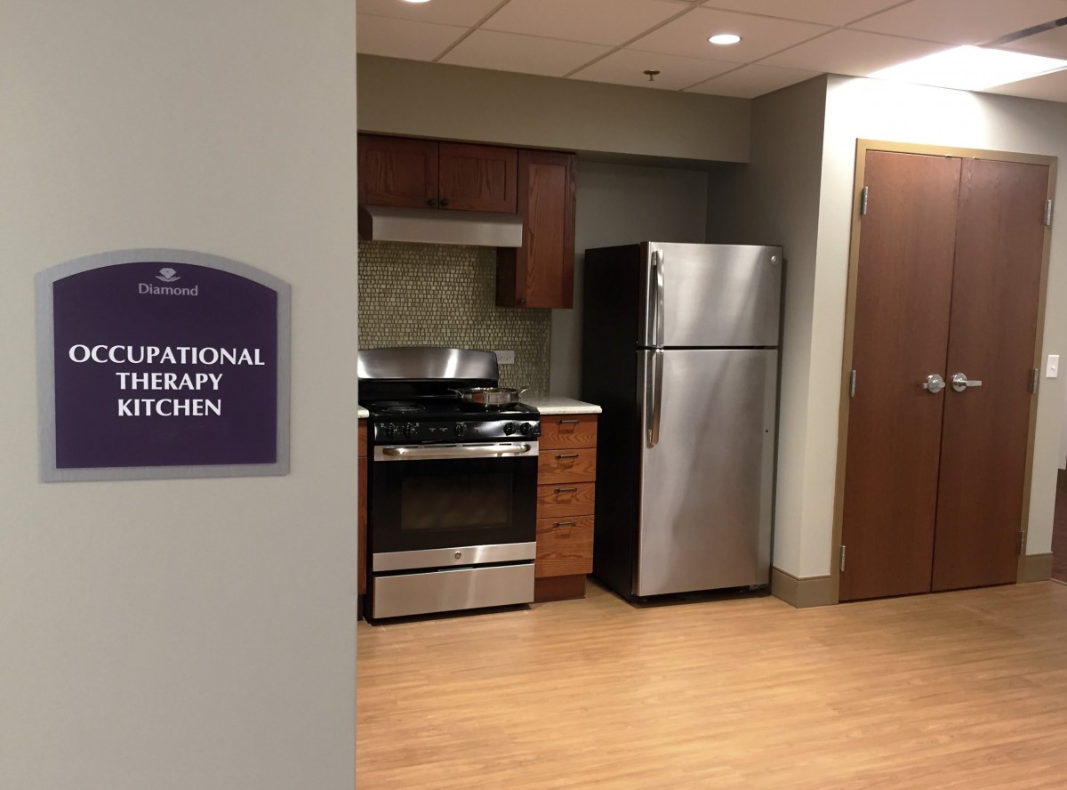 A modern therapy kitchen featuring a stove and refrigerator.