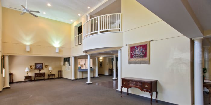 A spacious lobby area featuring a balcony, decorative columns, and classic furniture pieces.