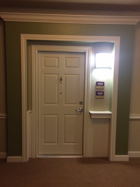 A neatly framed apartment door with a light fixture and room numbers displayed.