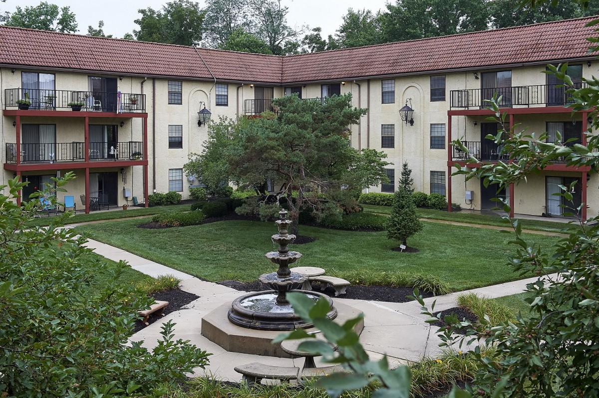 A peaceful apartment courtyard featuring a central fountain and lush landscaping.
