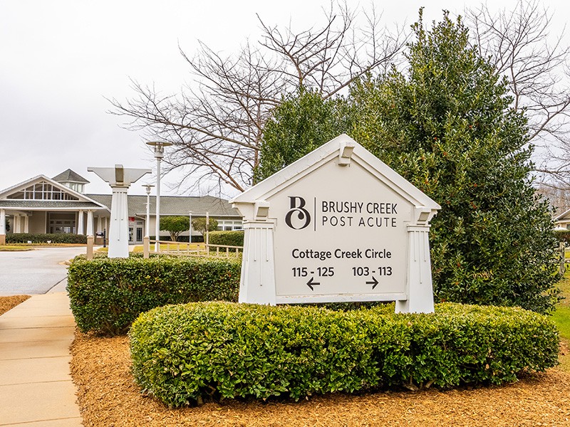A sign in front of a residential building surrounded by greenery.