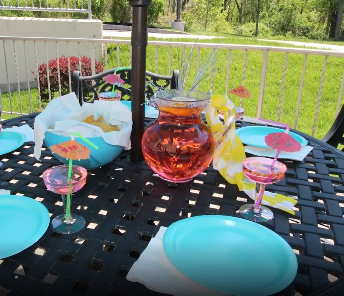 A colorful outdoor table setup with blue plates and refreshing drinks in a garden setting.