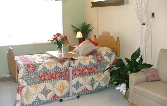 A cozy bedroom scene with a quilt-covered bed, flowers, and decorative plants.