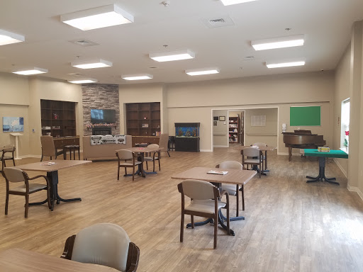 A spacious and well-lit interior room with tables and chairs arranged for activities.