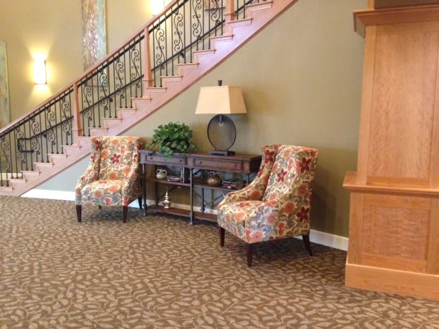 A cozy seating area with floral chairs and a decorative staircase.