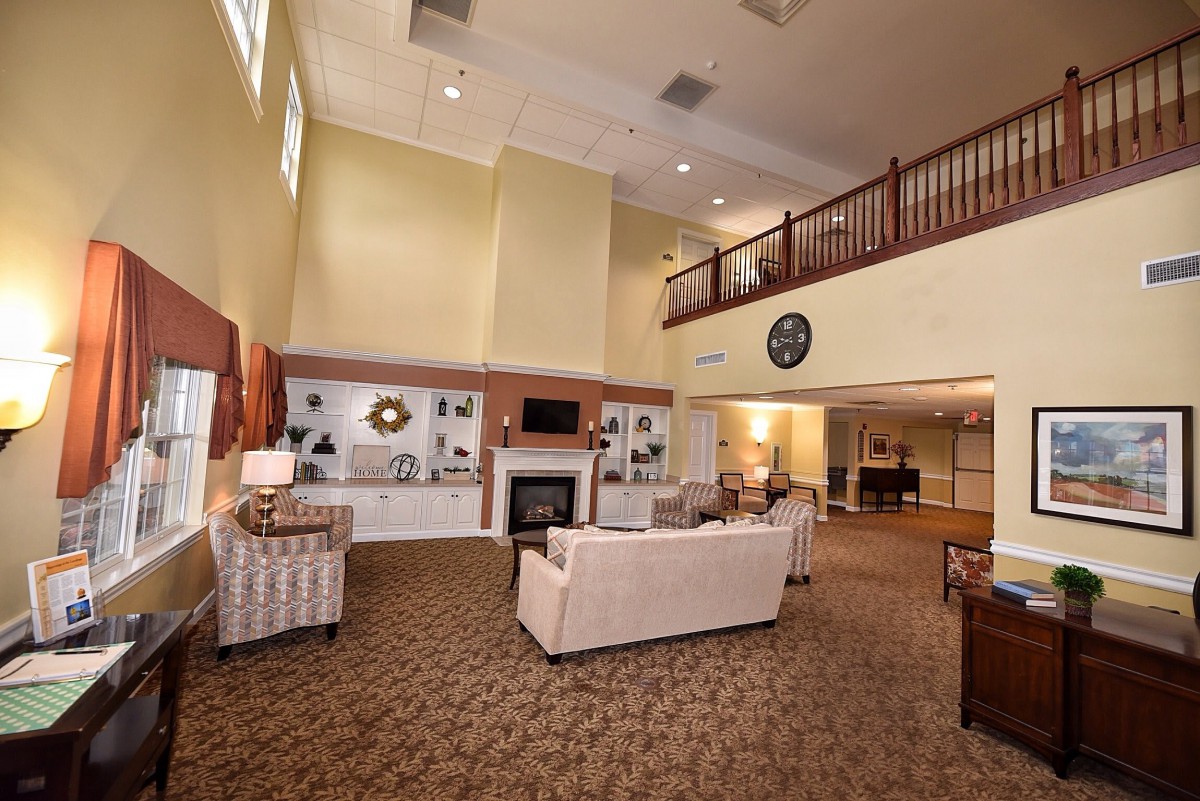A spacious living room with a high ceiling, featuring comfortable seating and a fireplace.