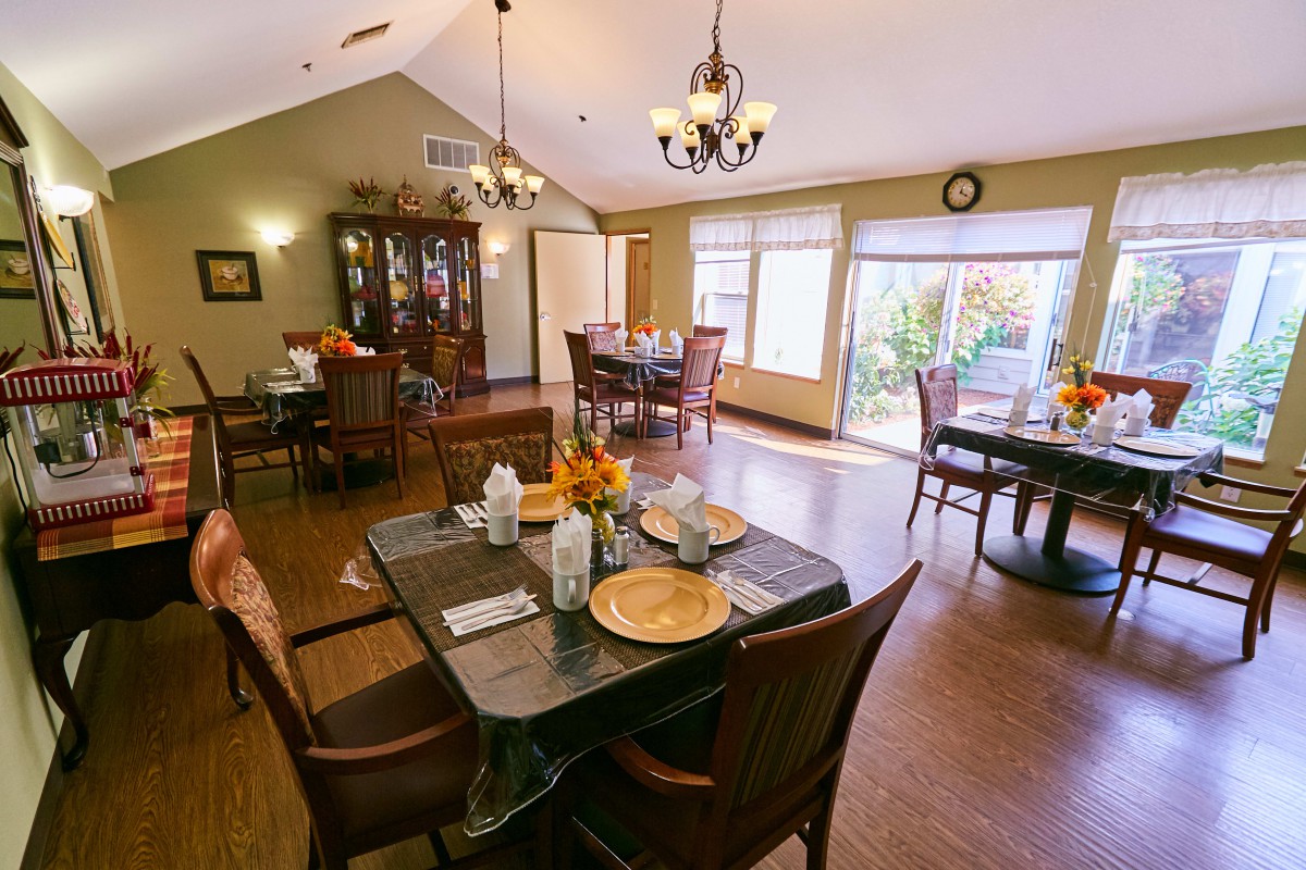 A well-lit dining room with elegantly set tables and chandeliers.