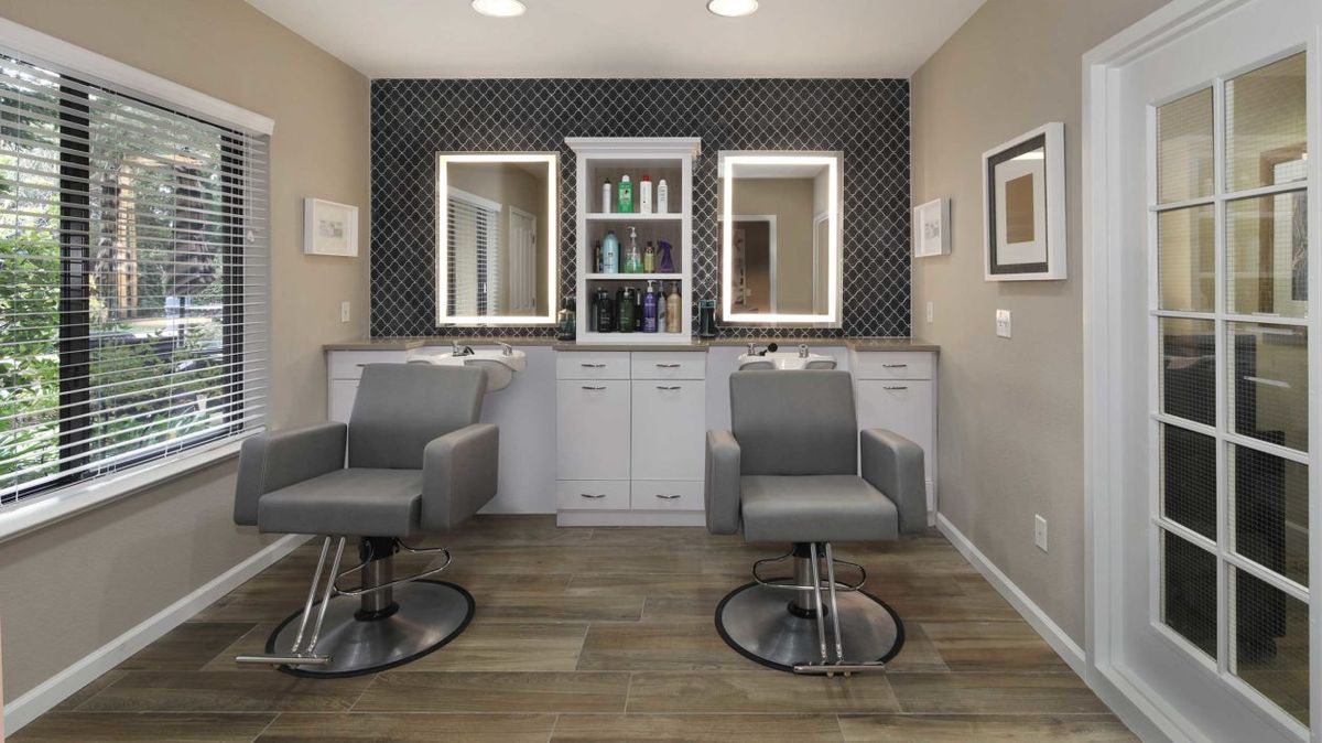 A modern hair salon interior with stylish chairs and illuminated mirrors.