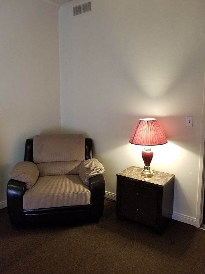 A cozy corner with an armchair, side table, and lamp.