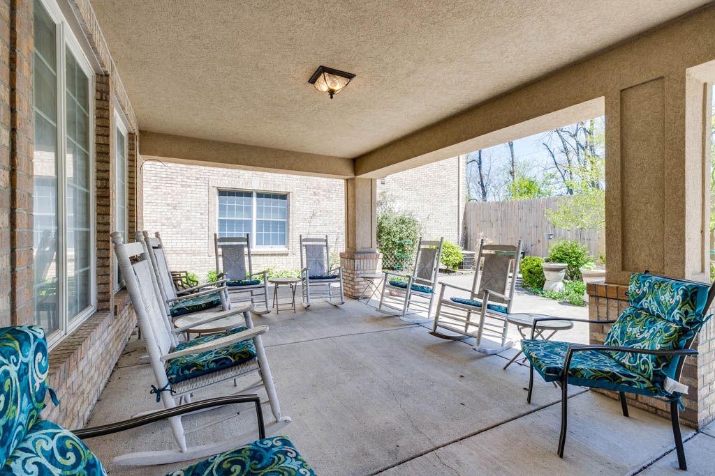 A cozy covered patio with rocking chairs overlooking a garden.