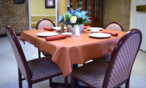 A beautifully arranged dining table featuring an orange tablecloth, elegant plates, and a floral centerpiece.