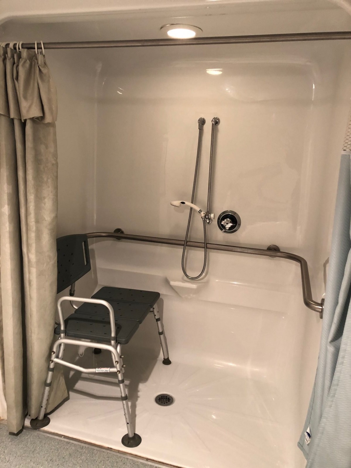 An accessible bathroom with a shower chair and grab bars.