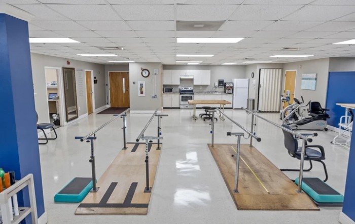 A physical therapy room equipped with parallel bars and other rehabilitation equipment.