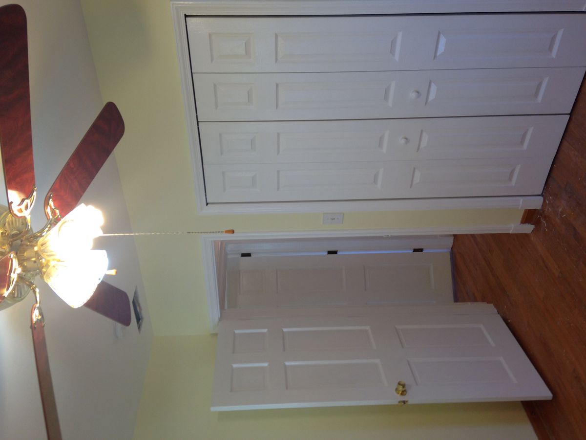 A room with a ceiling fan, closet doors, and wood flooring.
