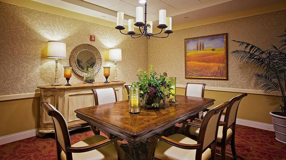 A cozy dining room featuring a wooden table, chairs, elegant chandelier, and decorative elements such as a mirror and painting.
