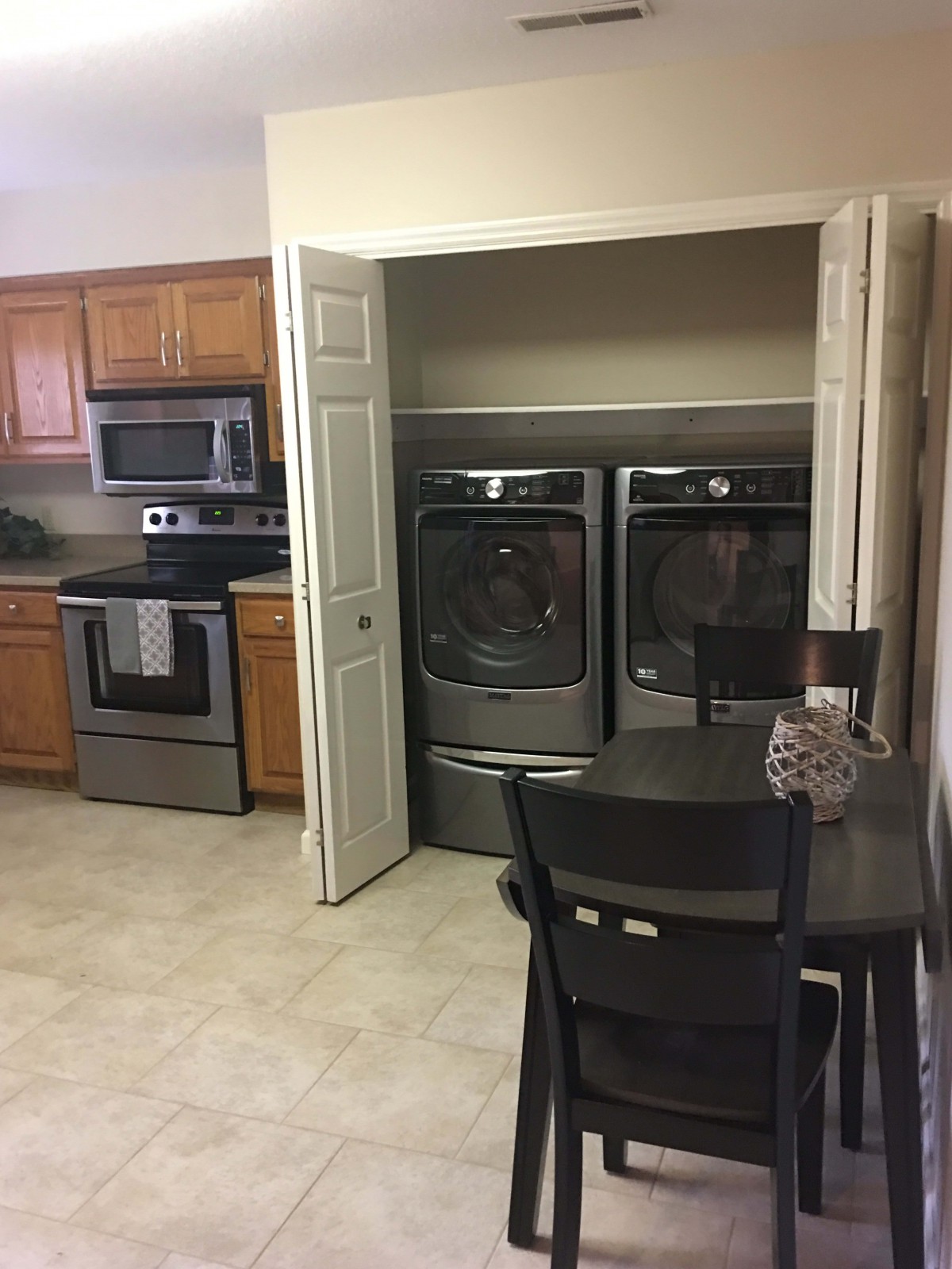 A modern kitchen with stainless steel appliances and a laundry area.