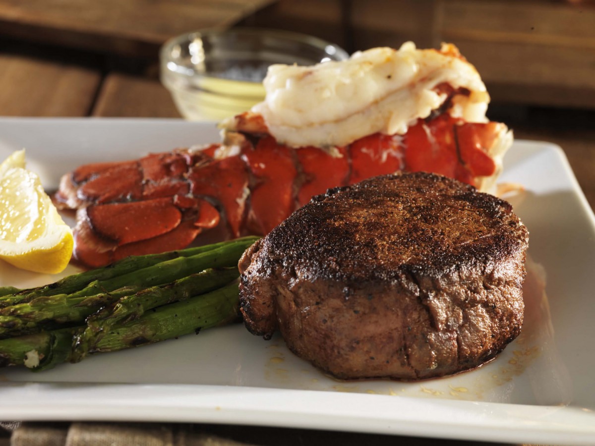 A gourmet meal featuring a perfectly cooked steak, lobster tail, and asparagus.