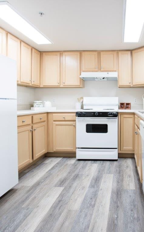 A clean and organized kitchen with light wooden cabinets and modern appliances.