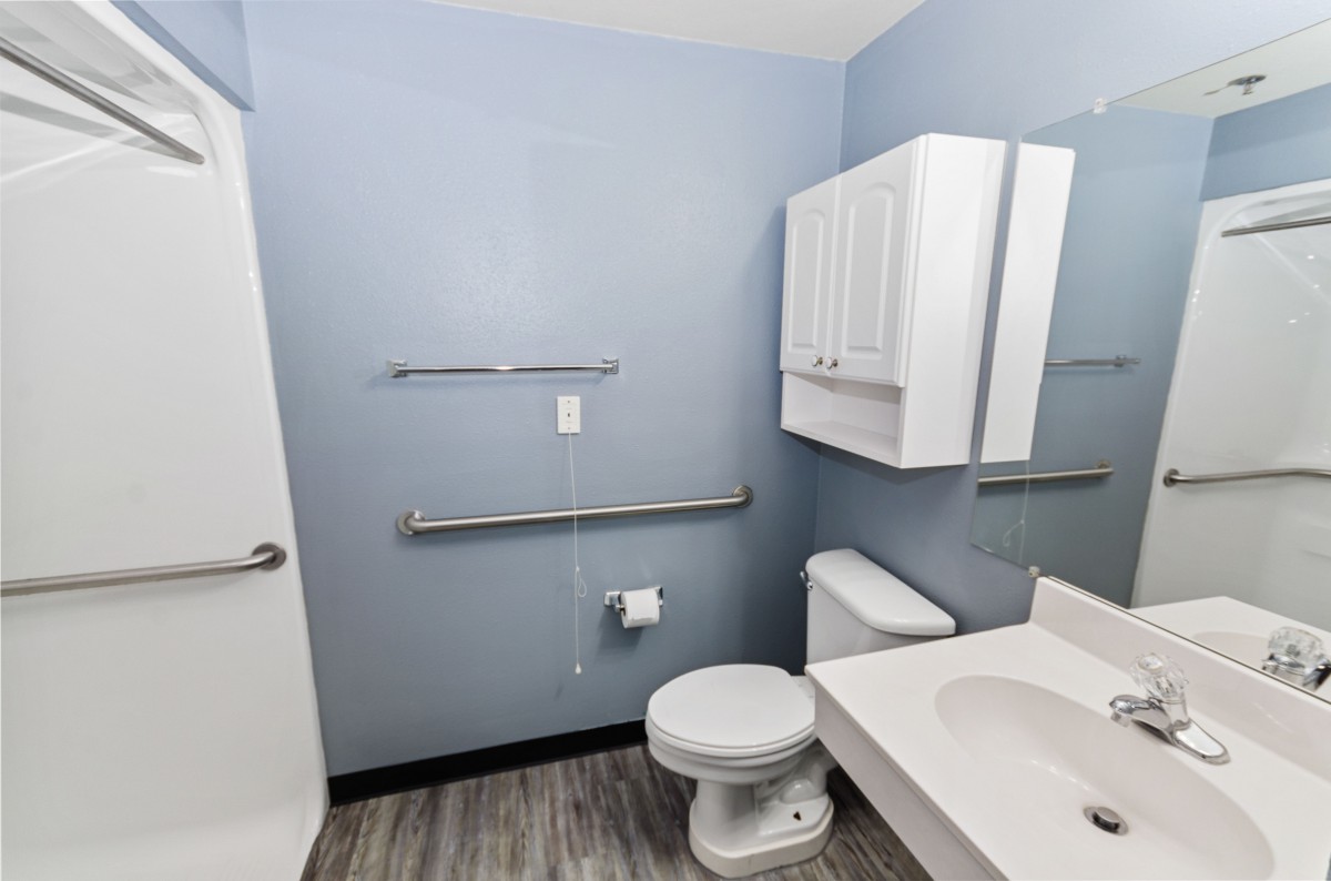 A modern bathroom with blue walls featuring a toilet, sink, cabinet, and towel rack.