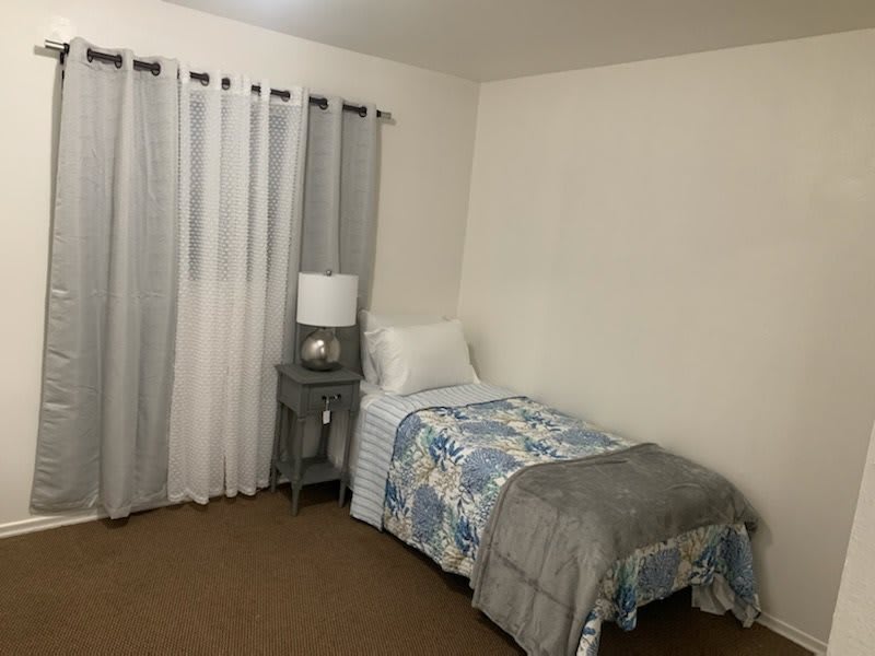 A cozy bedroom with a single bed and a bedside lamp.